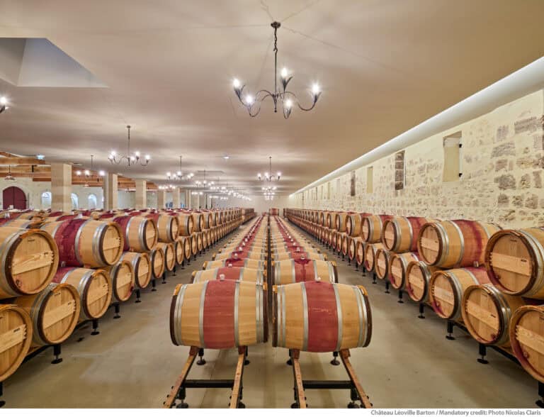 Chai traditionnel du Château Léoville Barton dans le Médoc, avec rangées de barriques en élevage, au cœur d’une visite œnologique à Bordeaux.