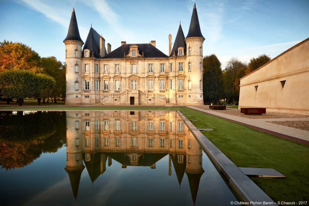 Façade majestueuse d’un château bordelais reflétée dans un bassin, symbole d’élégance et d’histoire au cœur du patrimoine viticole.