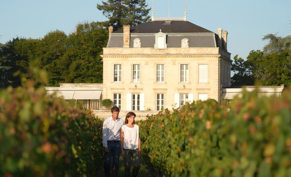 Couple en balade dans les vignes d’un château de Saint-Émilion, vivant une expérience œnologique élégante lors d’un weekend à Bordeaux.