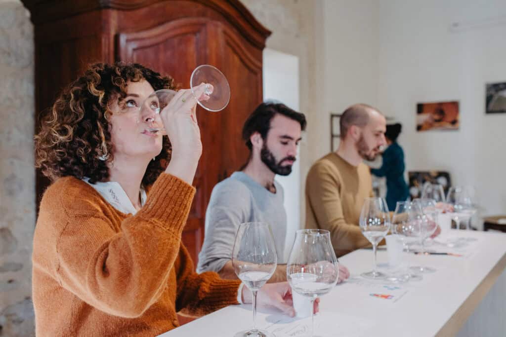 Participants en dégustation de vin dans un cadre élégant, découvrant les arômes lors d’une expérience œnologique à Bordeaux.