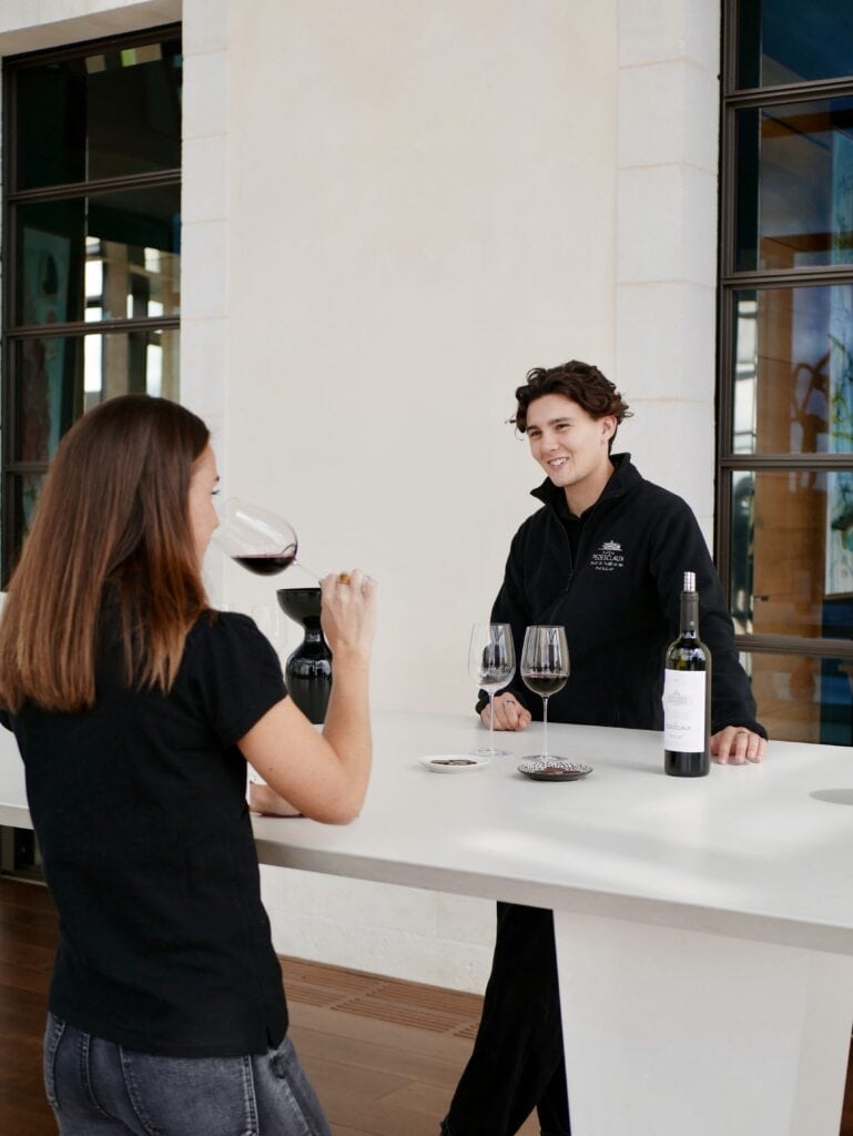 Échange entre une cliente et un expert lors d’une dégustation de vin à Bordeaux, illustrant une expérience œnologique accompagnée