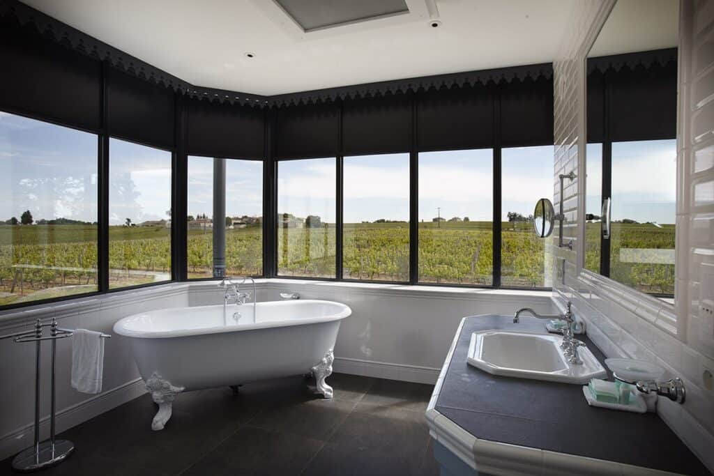 Salle de bain avec baignoire et vue sur les vignes dans un château viticole du vignoble bordelais